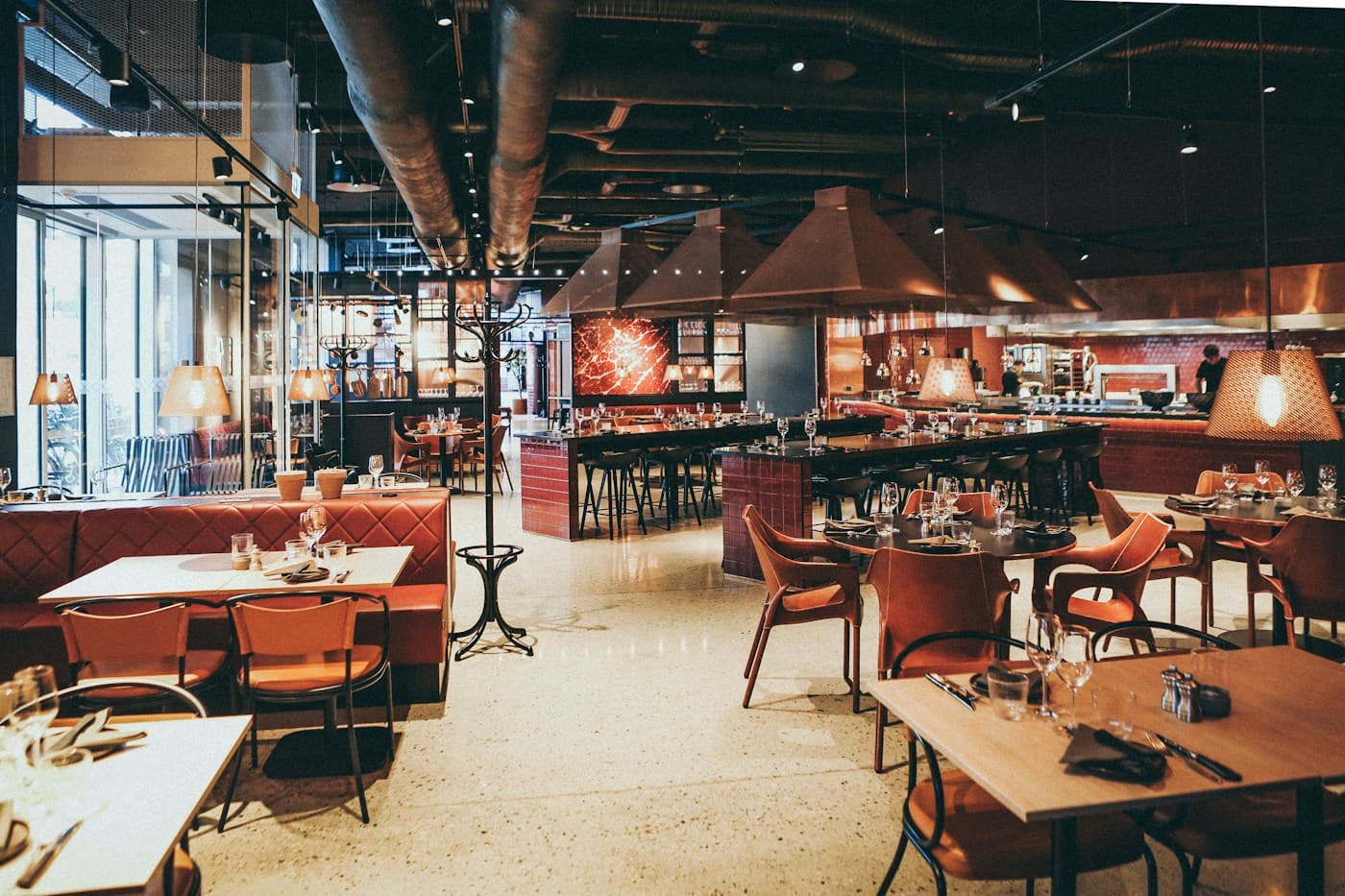 A hospitality dining space with prepared tables and an open service kitchen
